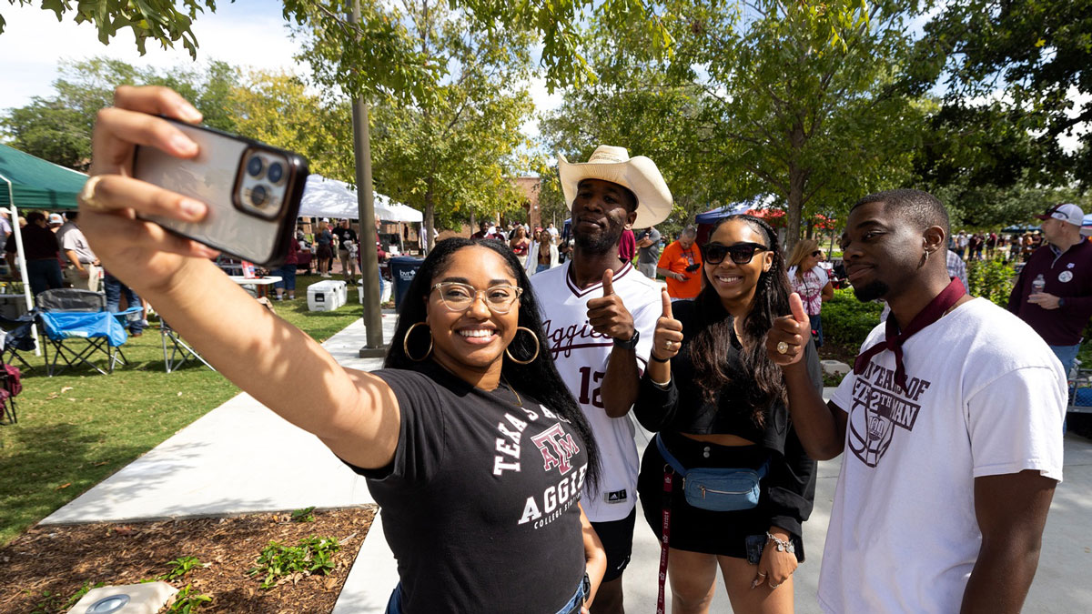 Four Texas A&M studdents pose for a selfie while tailgating at an 91Ƶ football game
