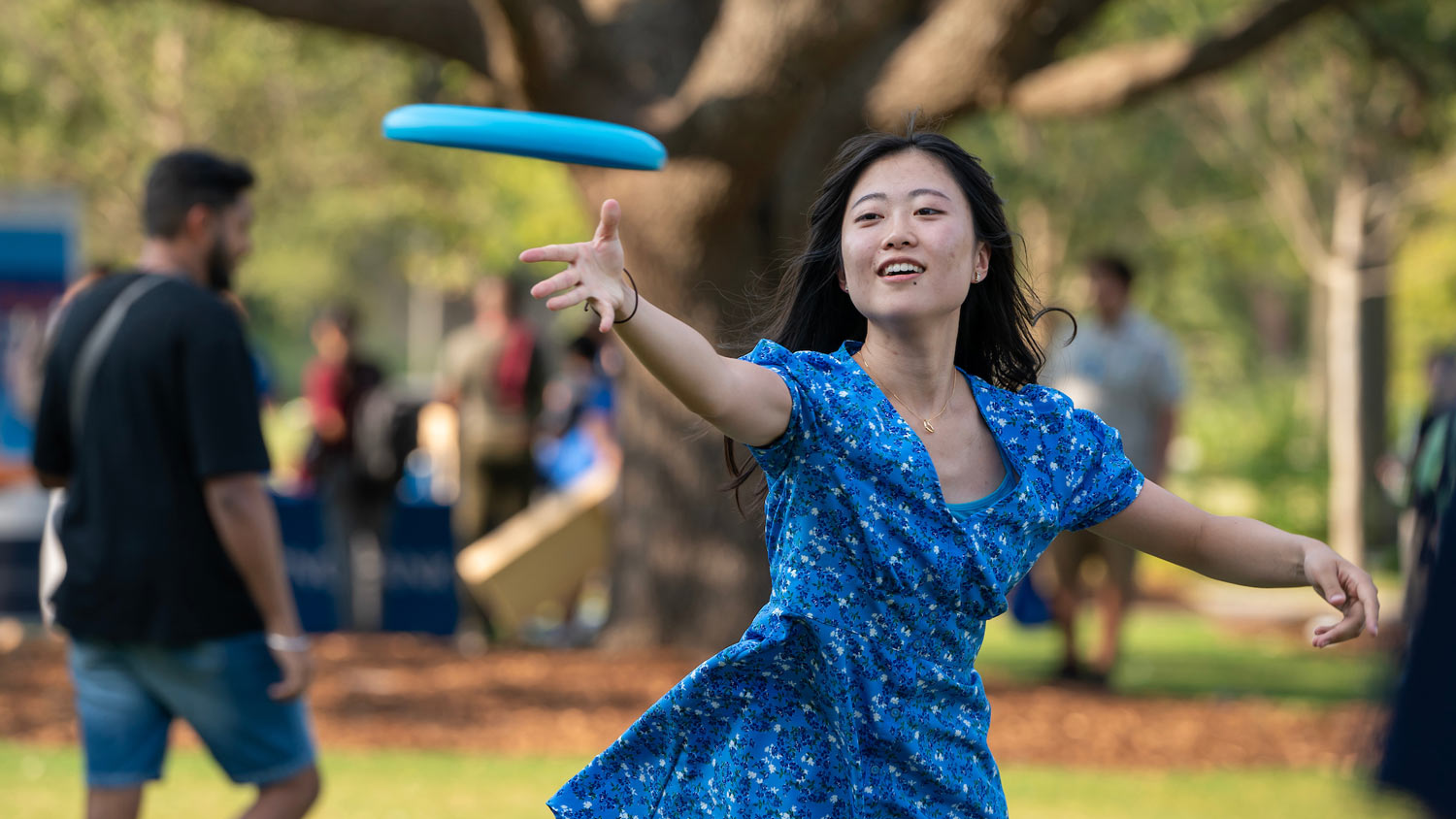 A student tosses a frisbee while at an event in 91Ƶ Park