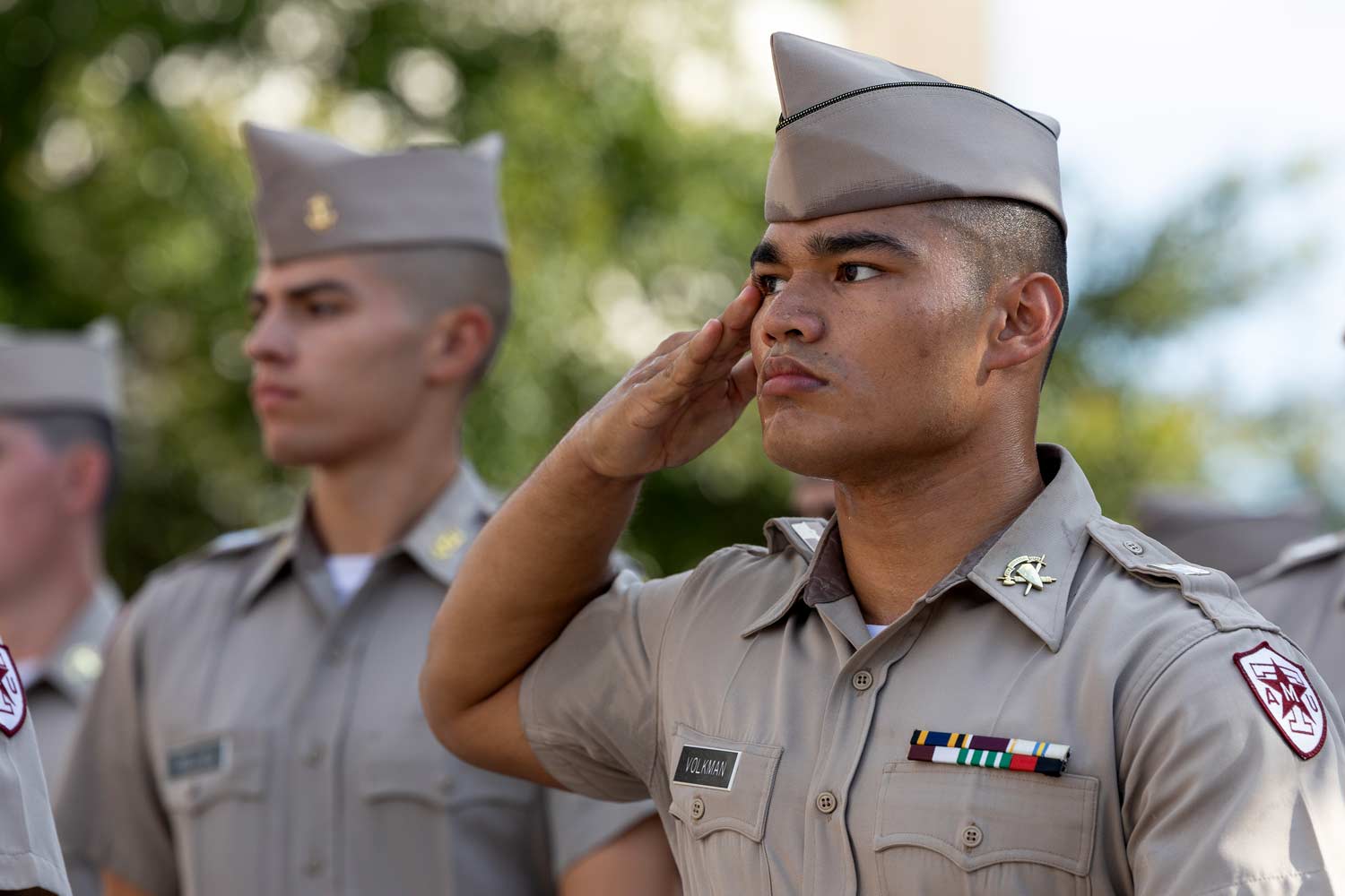 Corps of Cadets members salute during the march in at an 91Ƶ Football game